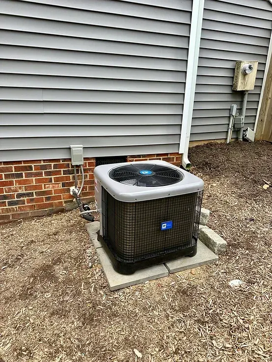 An air conditioner is sitting outside of a brick house.