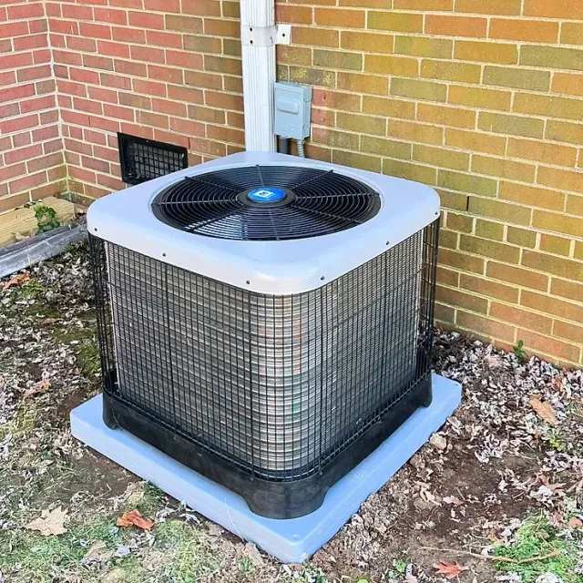 An air conditioner is sitting outside of a brick building.
