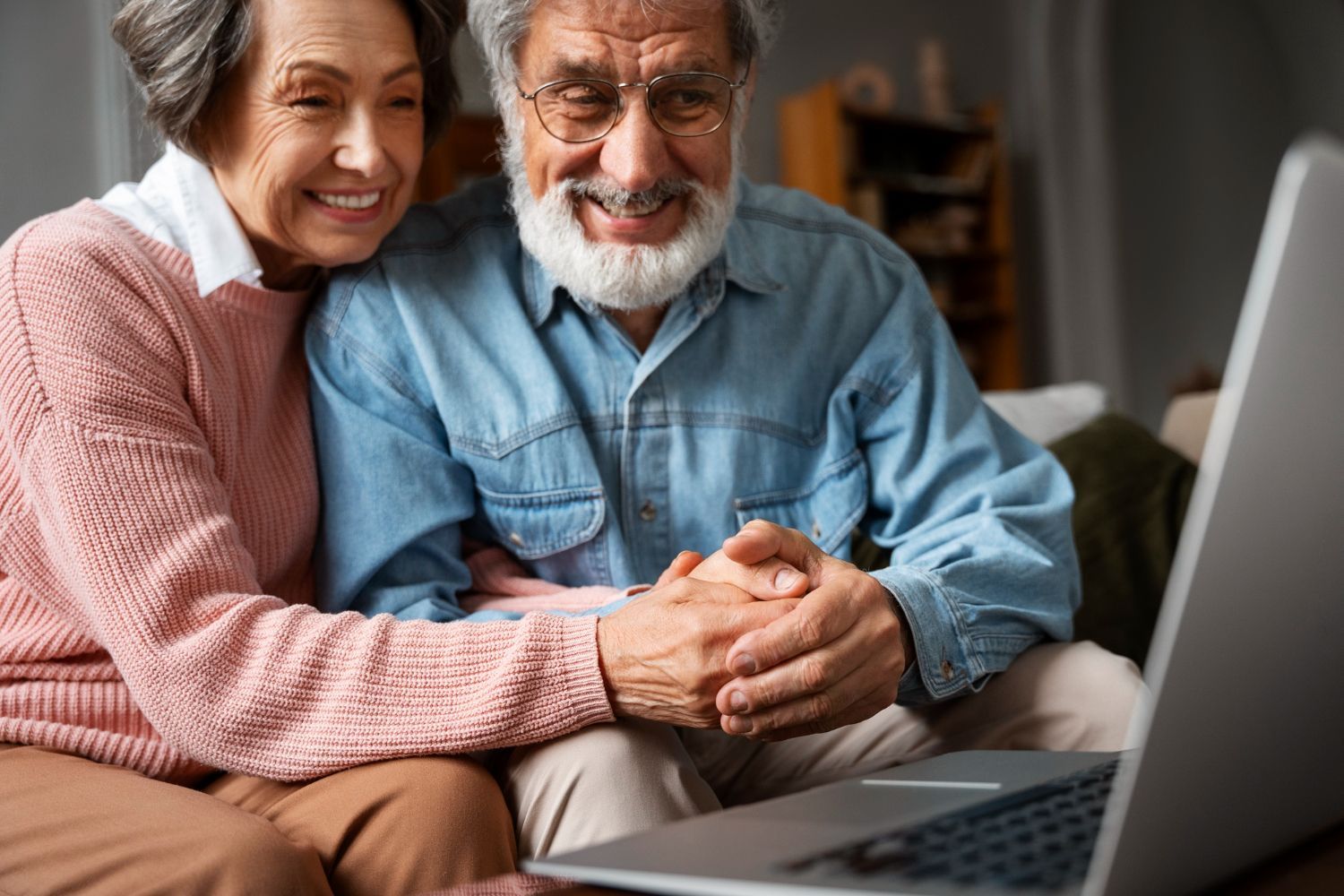 Smiling couple on a couch looking at a laptop together