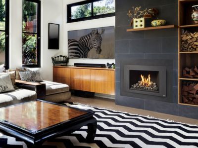 A modern living room with a fireplace, zebra-print TV screen, wood cabinets, and a black-and-white chevron area rug.