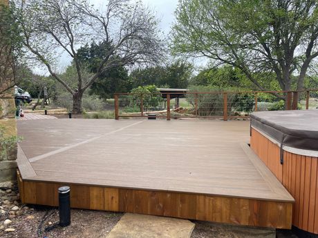 Wooden deck with a hot tub and trees in a backyard setting.