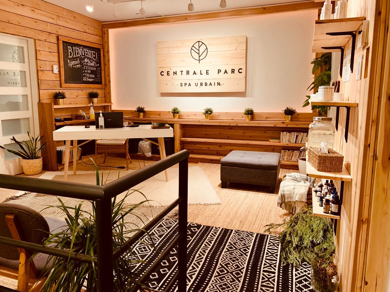 Réception du Spa Centrale Parc avec son comptoir d'accueil, des boiseries chaleureuses, des plantes et une enseigne murale portant le logo du spa.