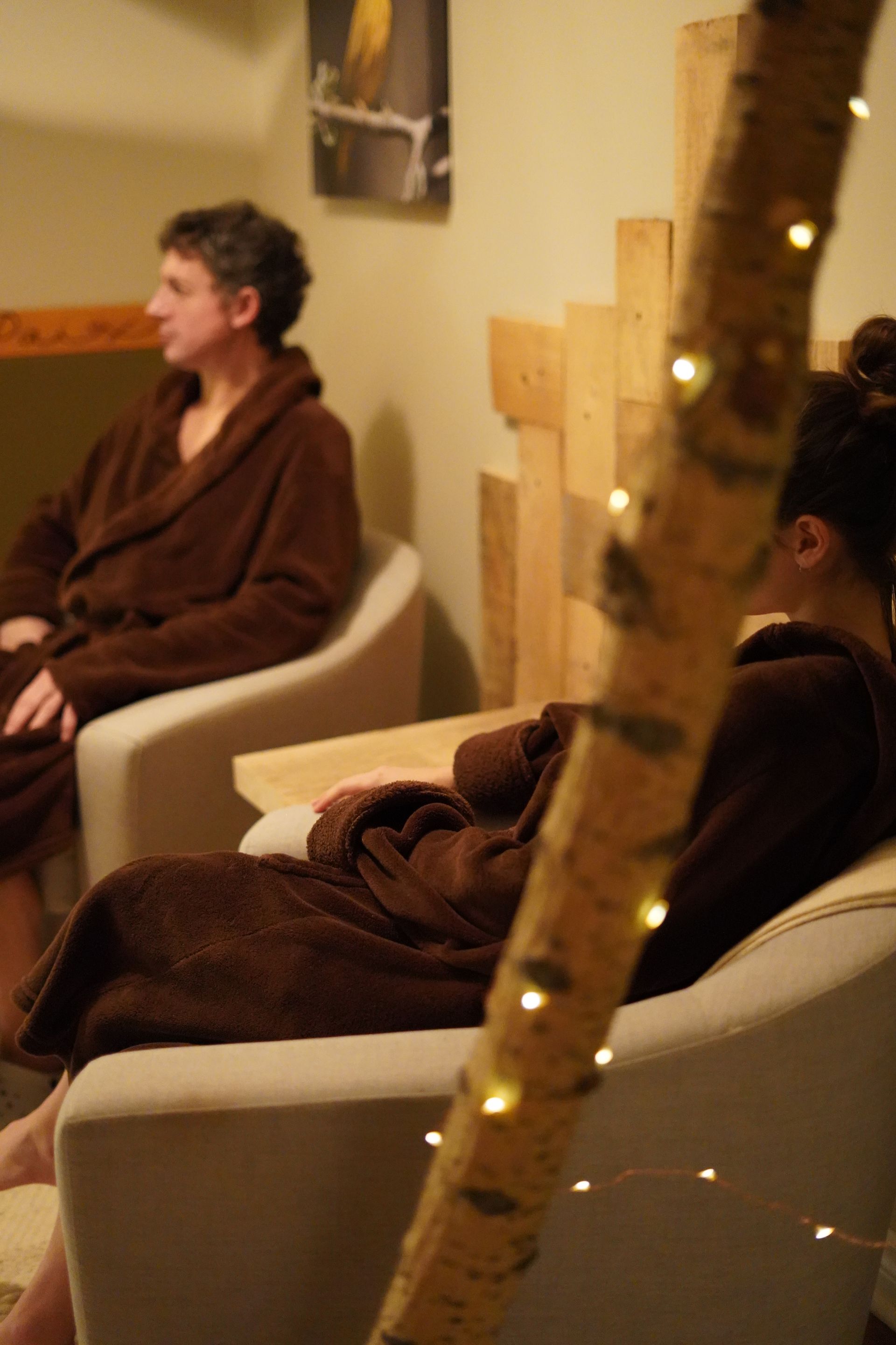 Clients du Spa Centrale Parc vêtus d’un peignoir profitant d'un moment de détente dans le salon avant ou après leur soin.