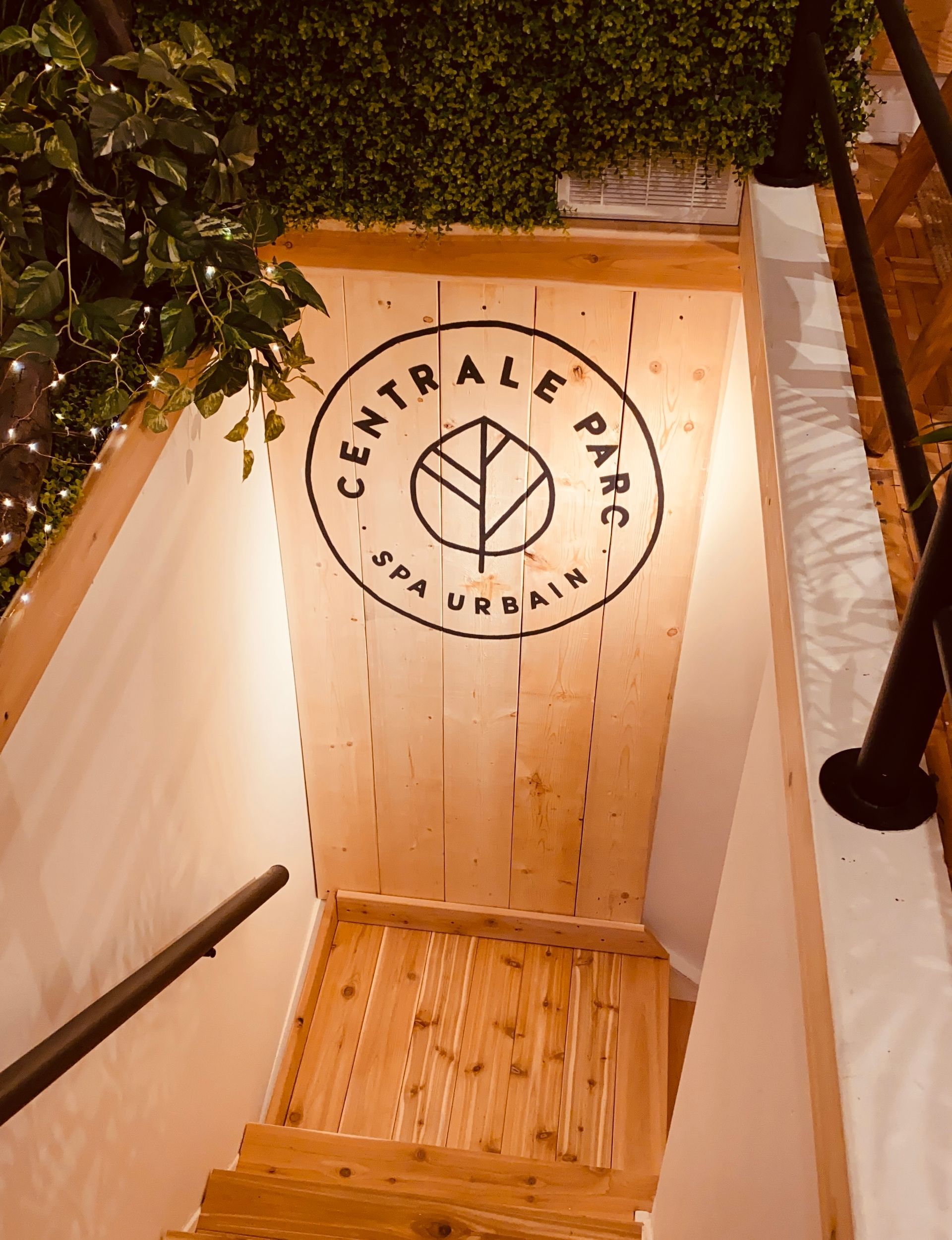 Escalier menant aux espaces de soins du Spa Centrale Parc, avec le logo du centre mis en valeur sur un mur de bois.