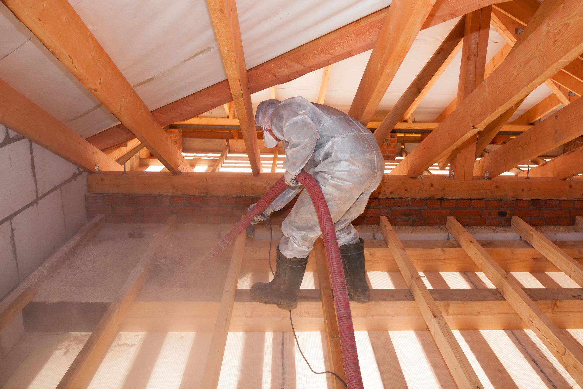 The ceiling of an attic with wooden beams and insulation.