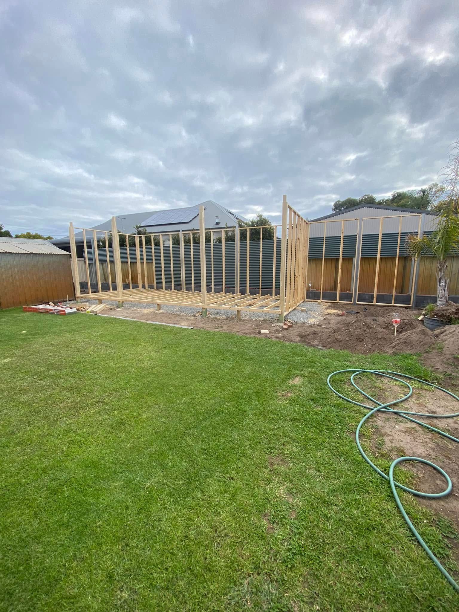 An outdoor timber and steel frame structure with a grey corrugated metal roof, currently under construction on concrete.