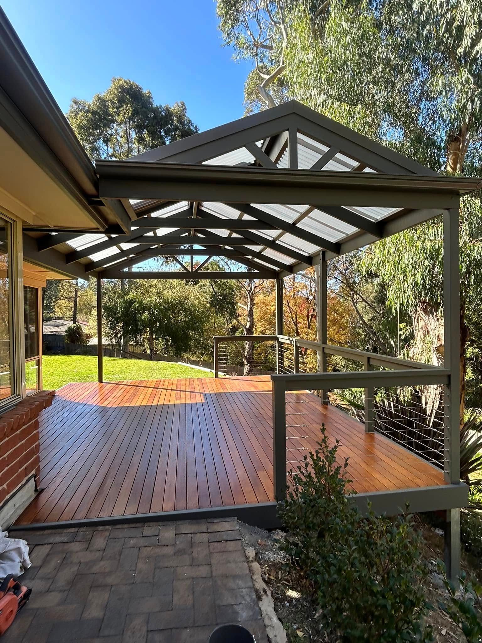 A swimming pool beside a polished wooden deck with two large decorative urns and a lounge chair.