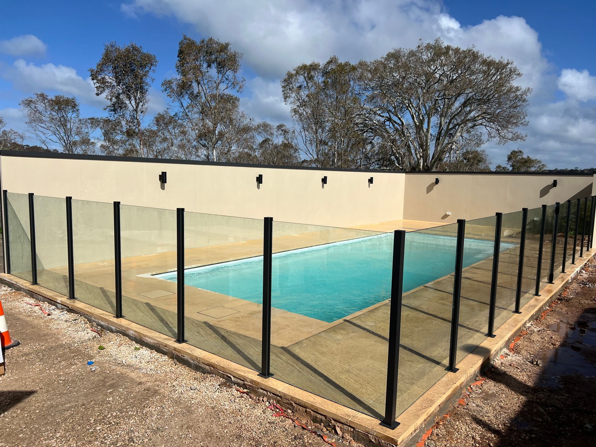 An oval swimming pool with a blue cover, set into a wooden deck outside a house with a covered patio.