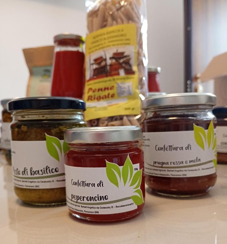Su un tavolo, vasetti di conserve e marmellate italiane, tra cui crema spalmabile al peperoncino e alle mele.