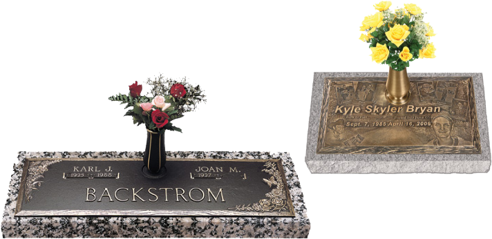 Two engraved grave markers with flower arrangements, one dark and one light gray, on a white background