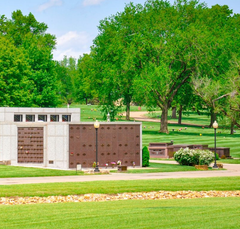 Modern cemetery with granite memorial walls, benches, and green trees in a landscaped park.