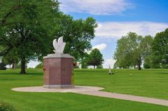 There is a statue of a dove in the middle of a cemetery.