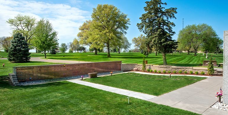Brick terraces and green lawns in a sunny park with trees and a paved walkway
