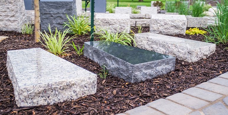 Modern stone benches around a landscaped garden with mulch and paving stones