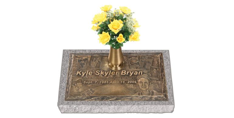 Memorial plaque with engraved name and yellow flowers placed on top