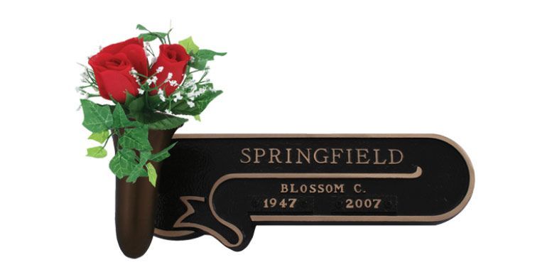 Black memorial plaque with red flowers reading