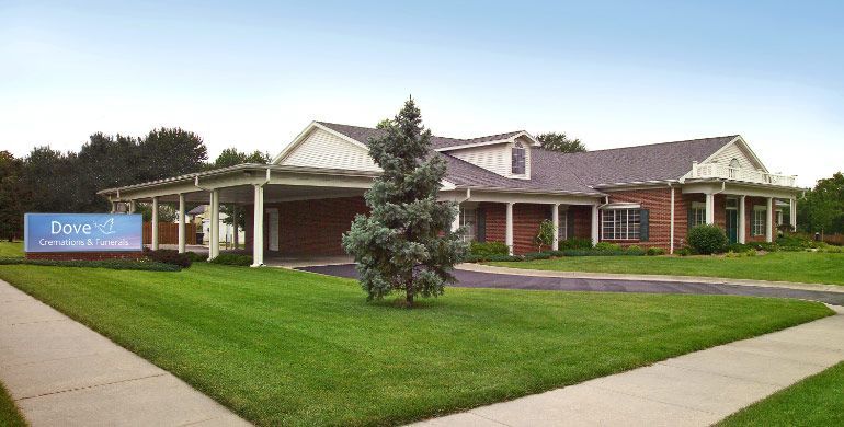 Single-story brick building with a sign, set behind a manicured lawn and sidewalk path