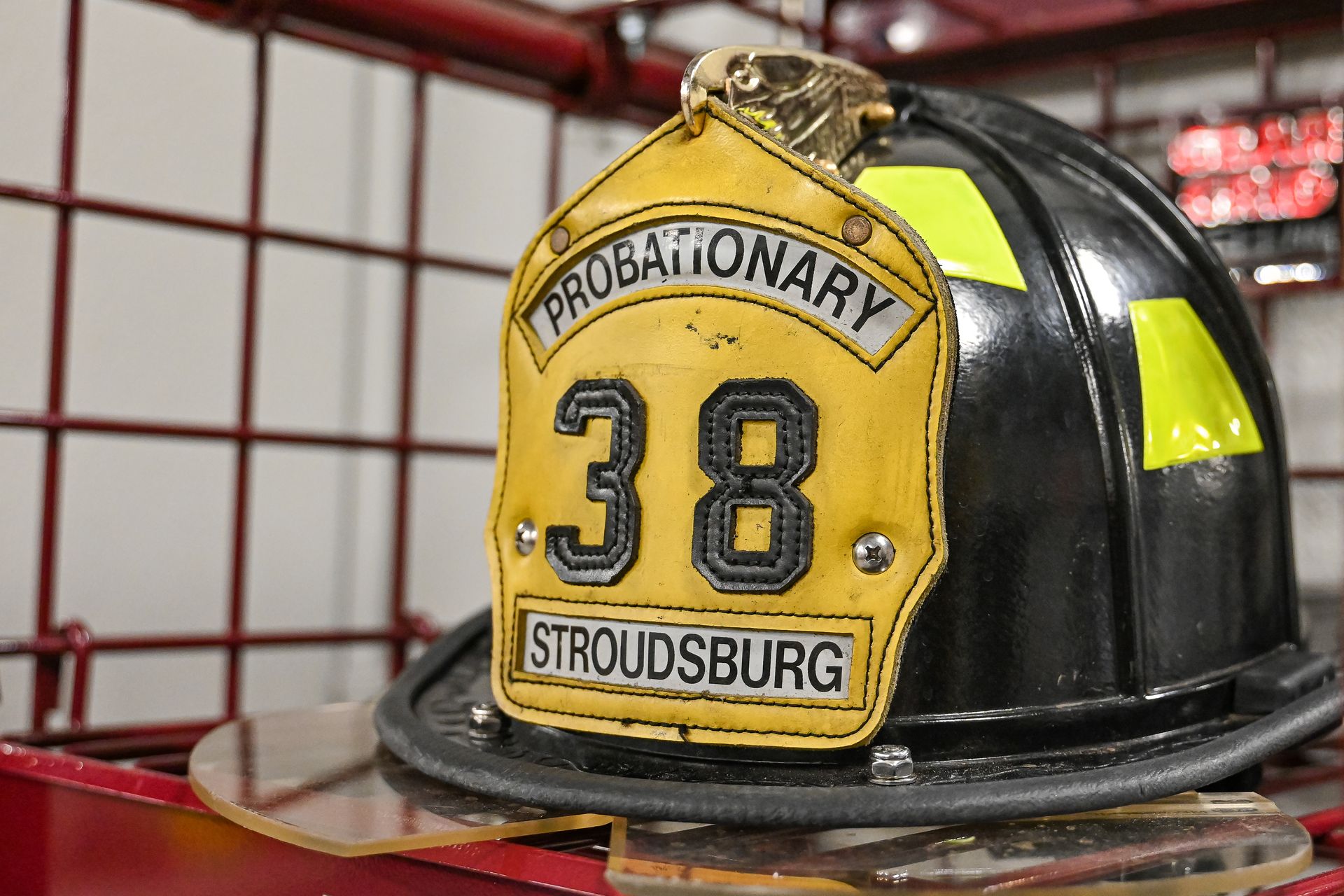 Black firefighter helmet with a yellow front shield labeled