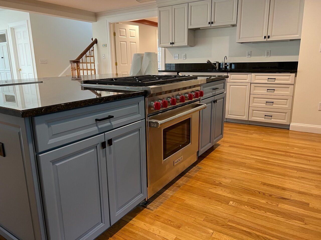 Modern kitchen with gray cabinets, black countertops, stainless steel range, and hardwood floors