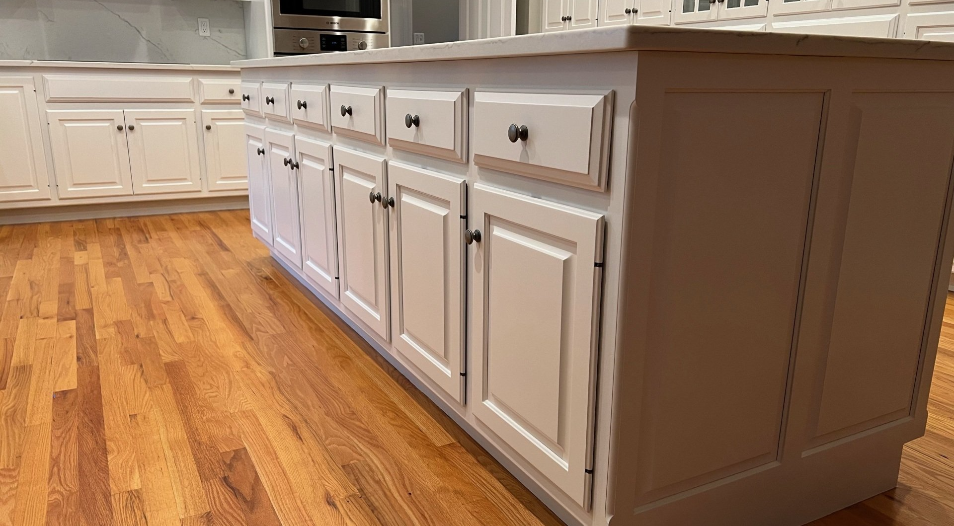 White kitchen cabinets with drawers along a polished hardwood floor