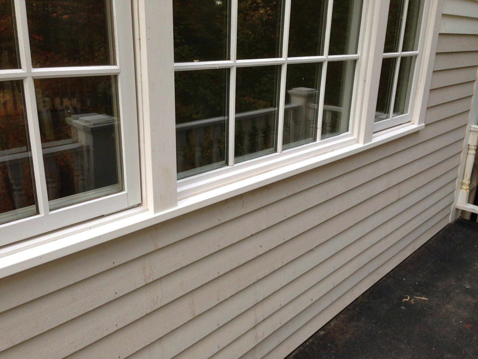 House exterior with beige siding and white-framed windows along a driveway