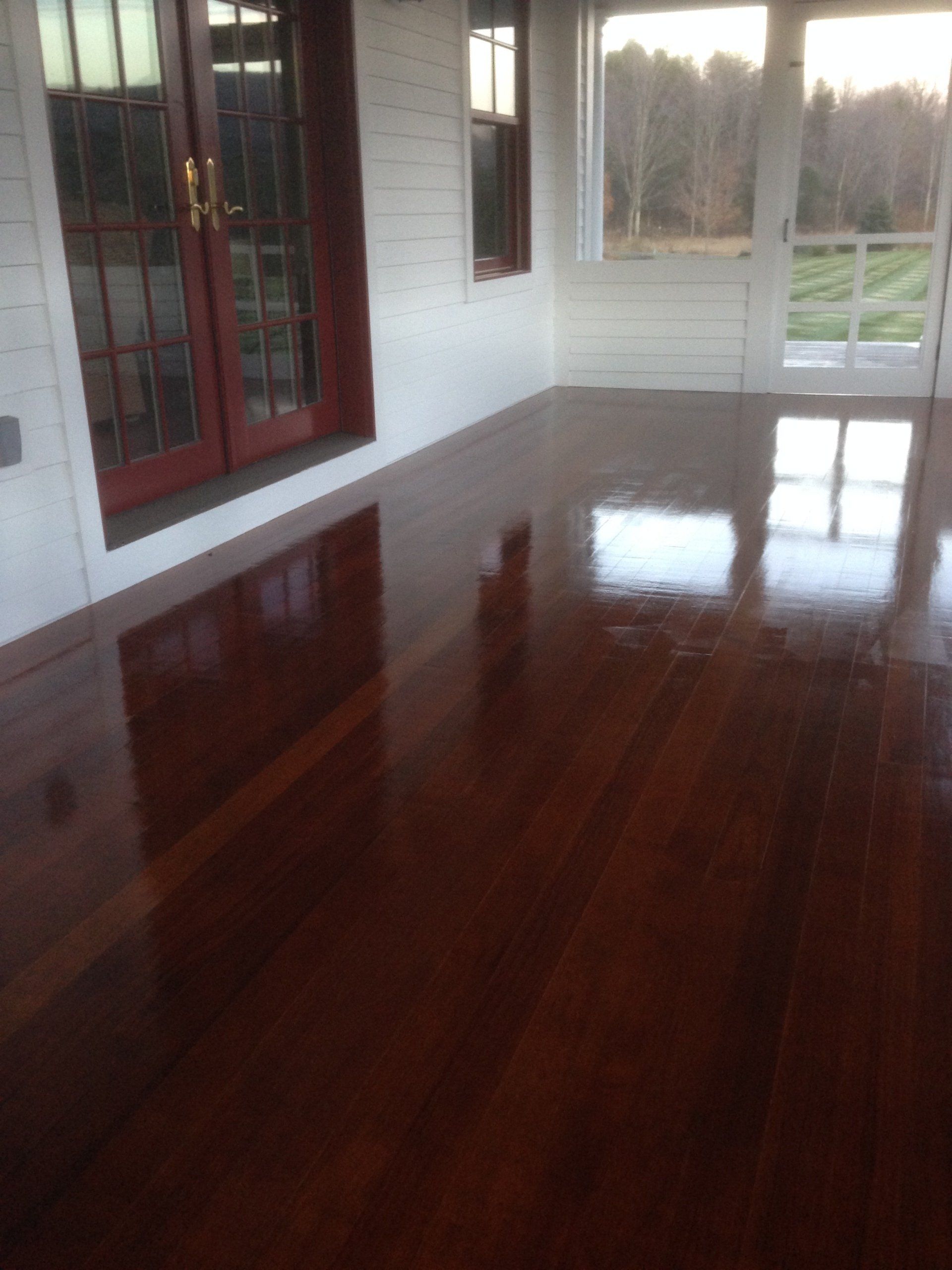 Empty room with glossy dark hardwood floors, white walls, and large windows overlooking outdoors
