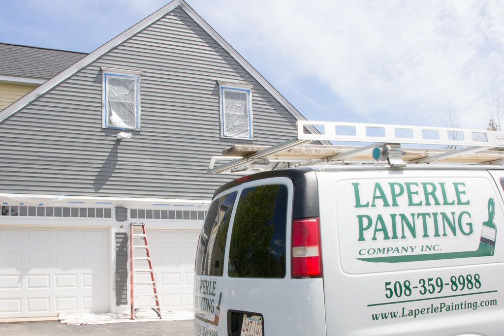 White Laprelle Painting van parked by a gray house with ladder, suggesting exterior painting work