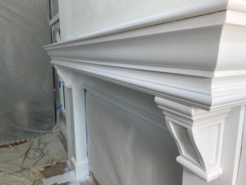 White decorative fireplace mantel with crown molding, viewed close up during interior renovation