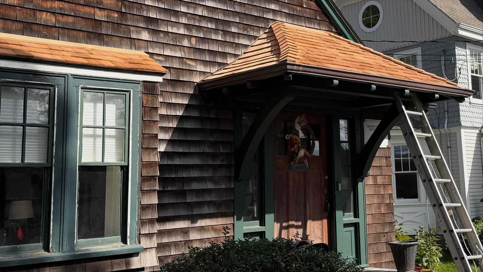 New cedar shingle roofs over front entrance and bay window on 1910 Granville C. Mitchell House in Medfield, MA