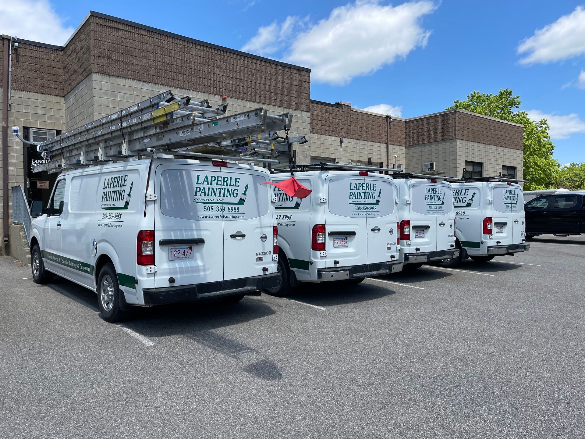 White service vans parked in a lot beside a brick building under a blue sky.