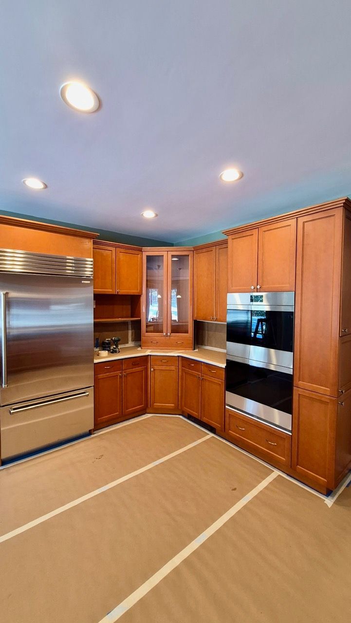 Before photo of Medfield MA kitchen with raised-panel wood cabinets in honey stain and stainless steel appliances before Laperle Painting transformation