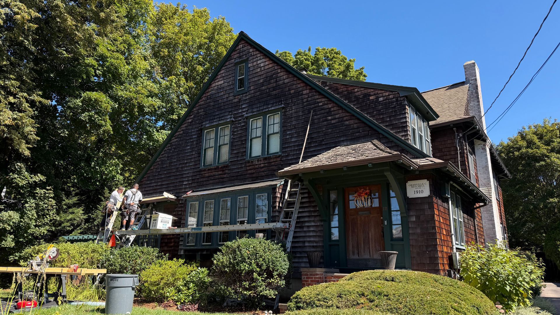 Carpentry crew working on a projecting window roof of a historic shingle-style home in Medfield, MA