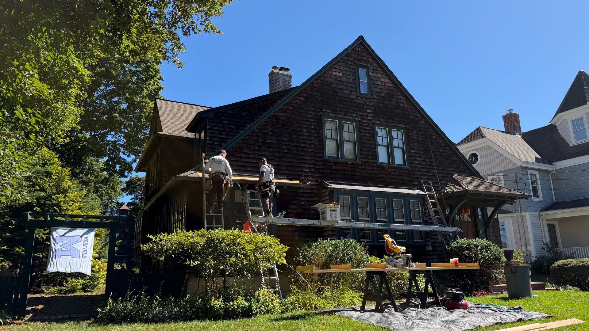Carpentry crew working on a projecting window roof of a historic shingle-style home in Medfield, MA