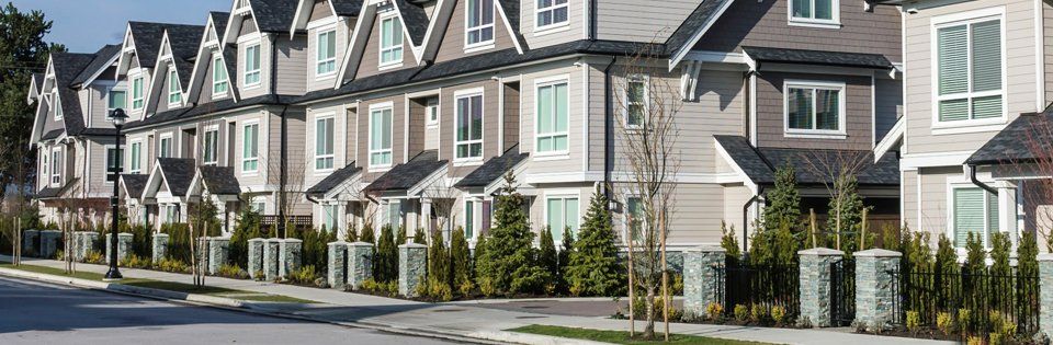 Row of modern townhouses with gabled roofs and small front gardens along a quiet street