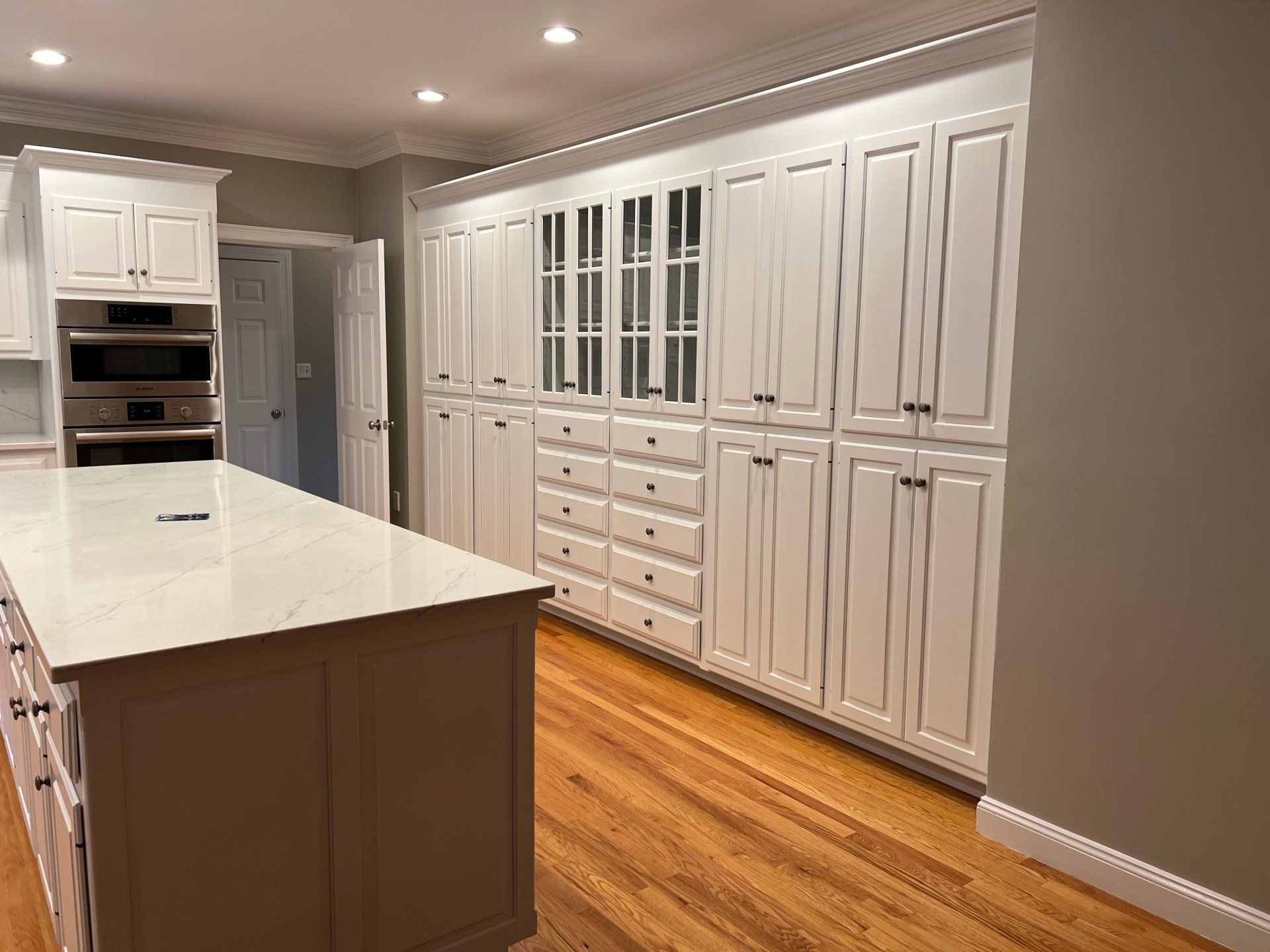 Bright white kitchen with large island, built-in cabinets, and hardwood floors