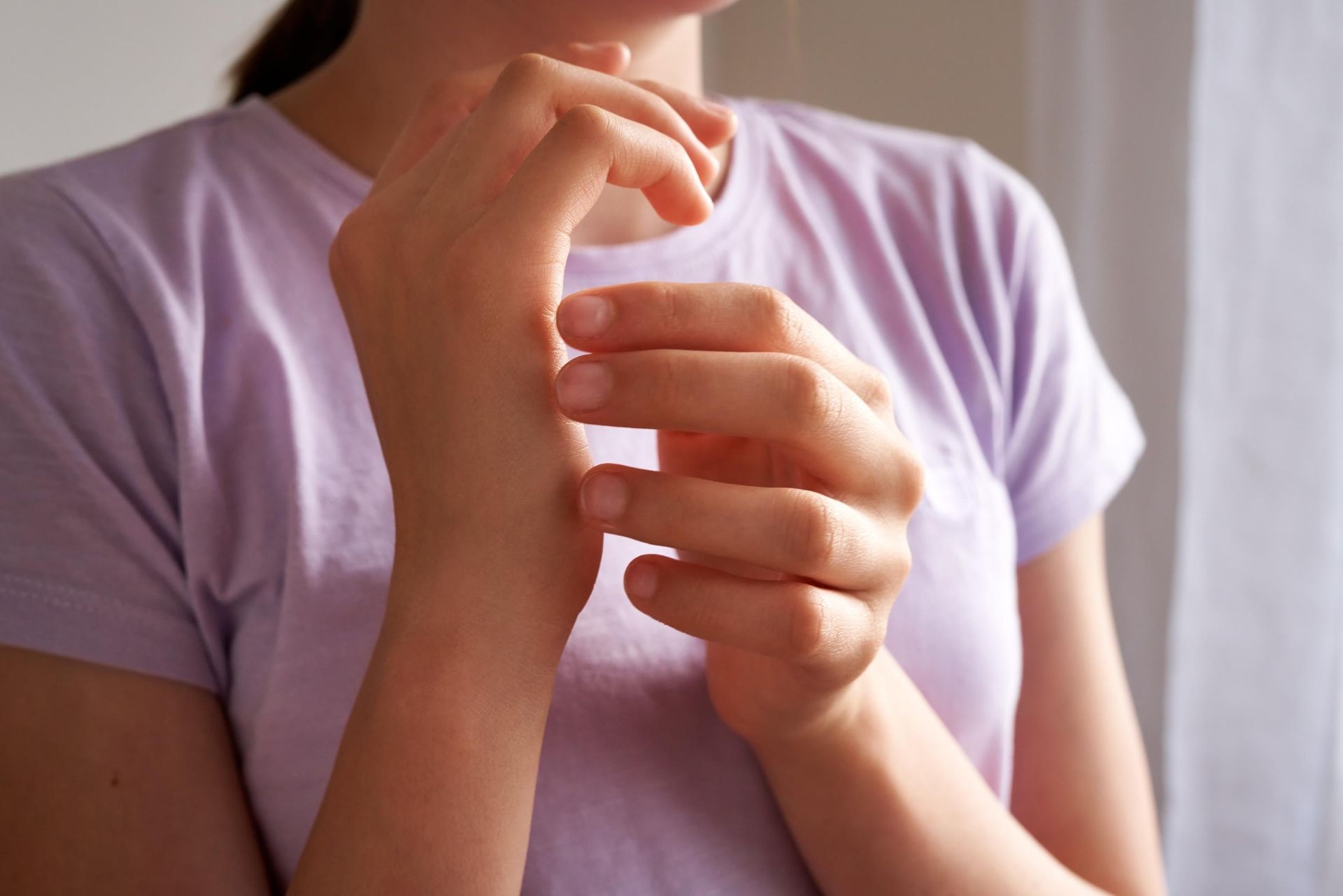 A woman in a purple shirt is rubbing her wrist.