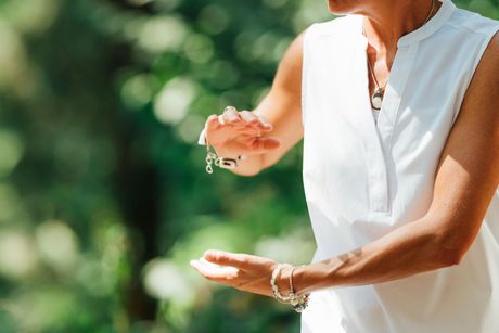 A woman in a white shirt is practicing tai chi outdoors.