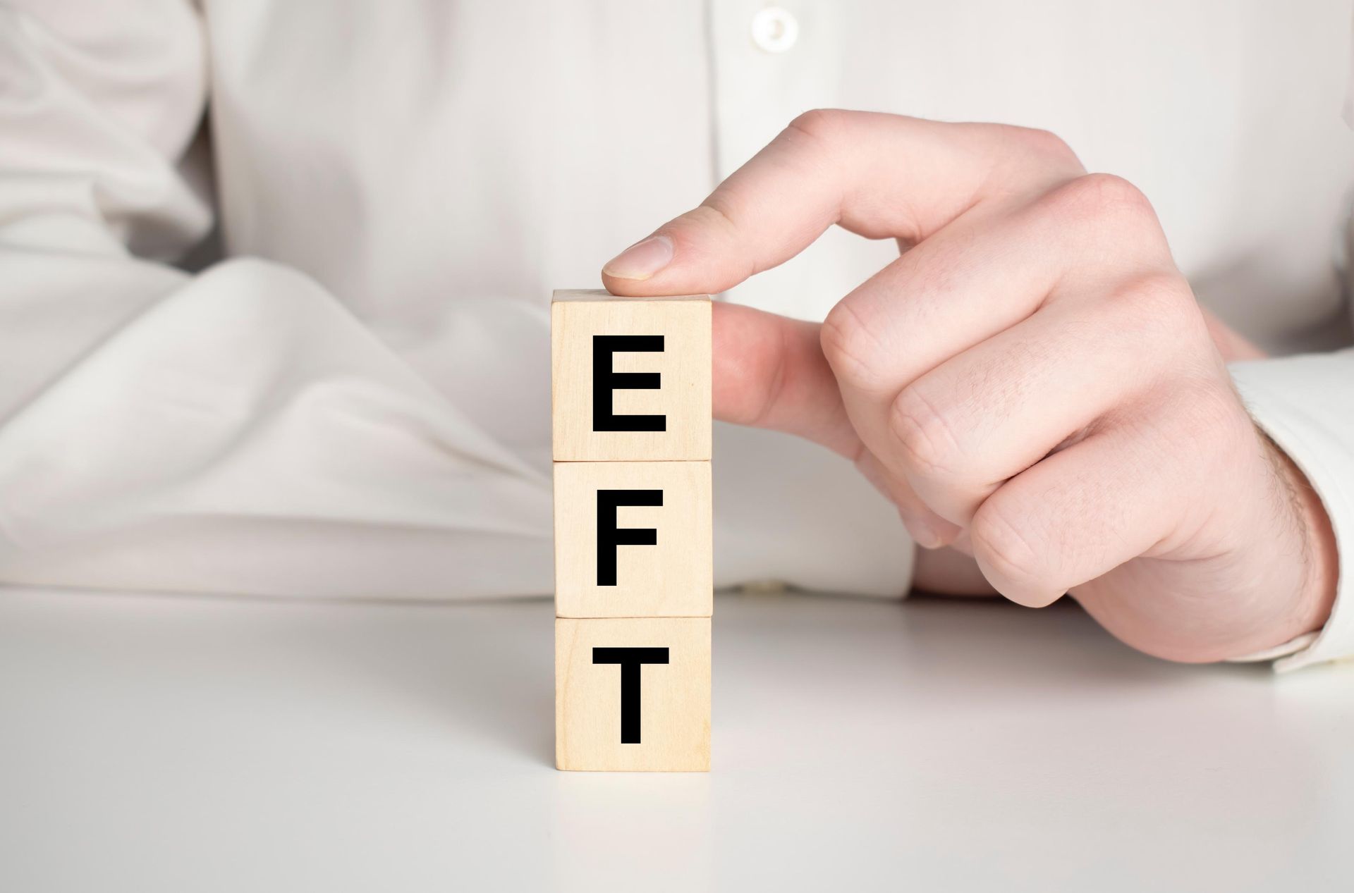 A person is holding a wooden block with the word eft written on it.