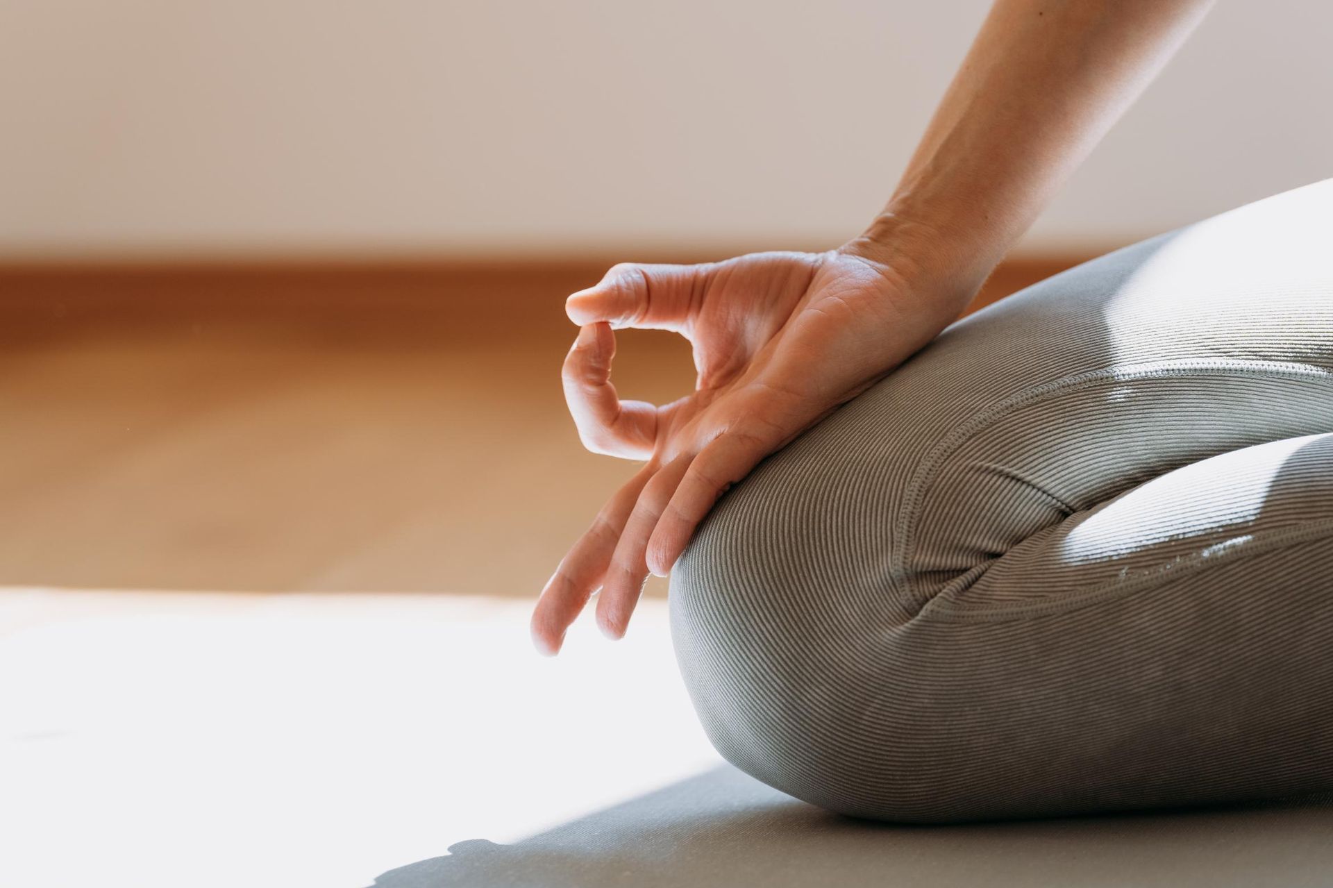 A person is sitting on the floor with their legs crossed and their hands in a lotus position.