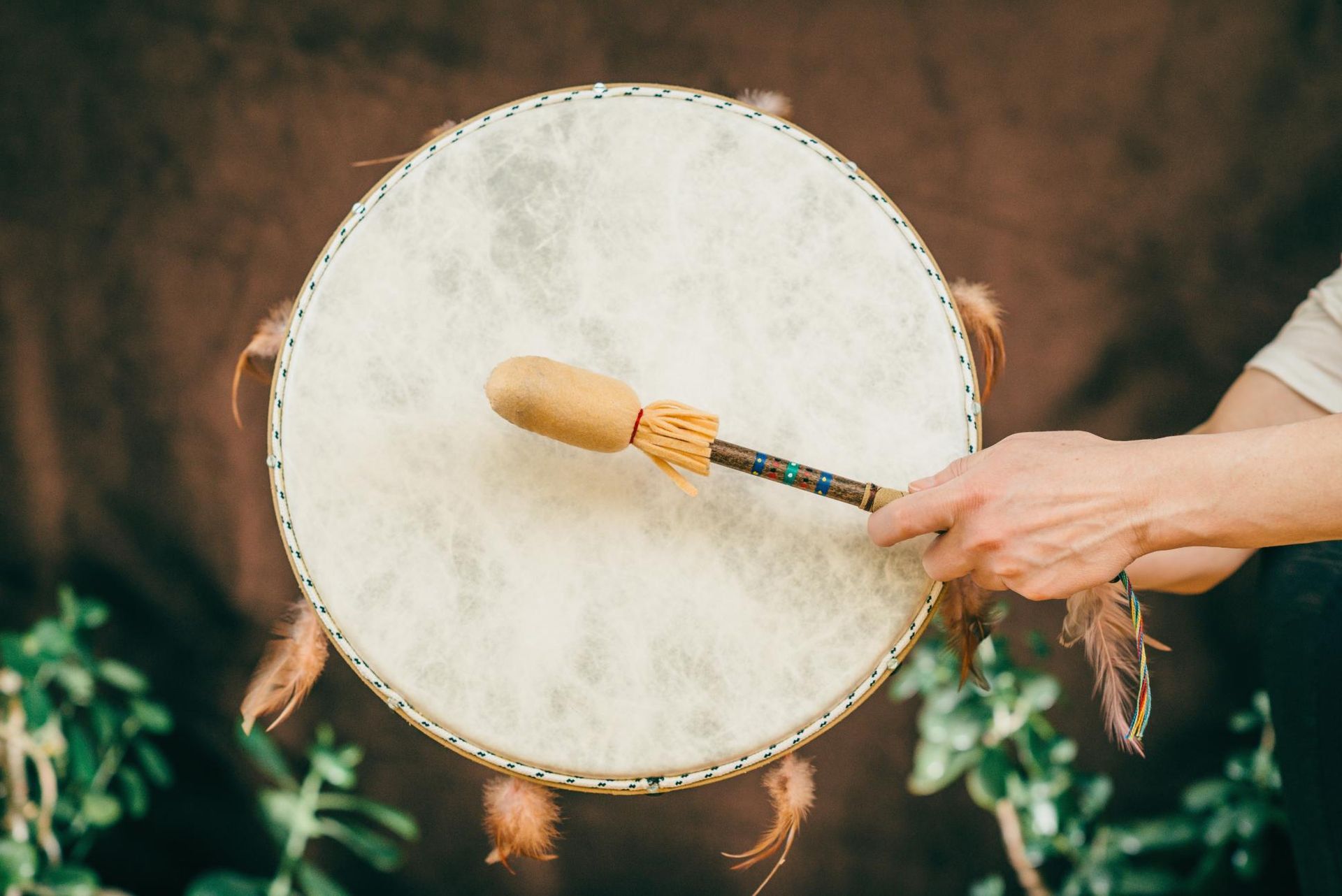 A person is playing a drum with feathers on it.