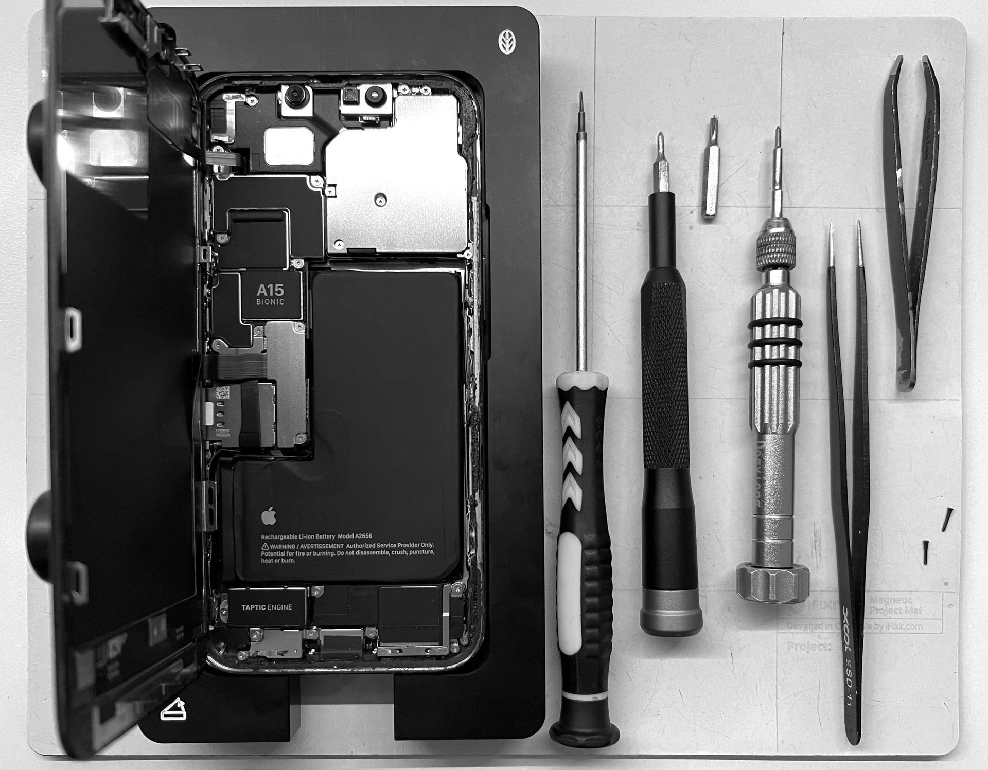 Phone that has screen lifted and screw driver with tools to side