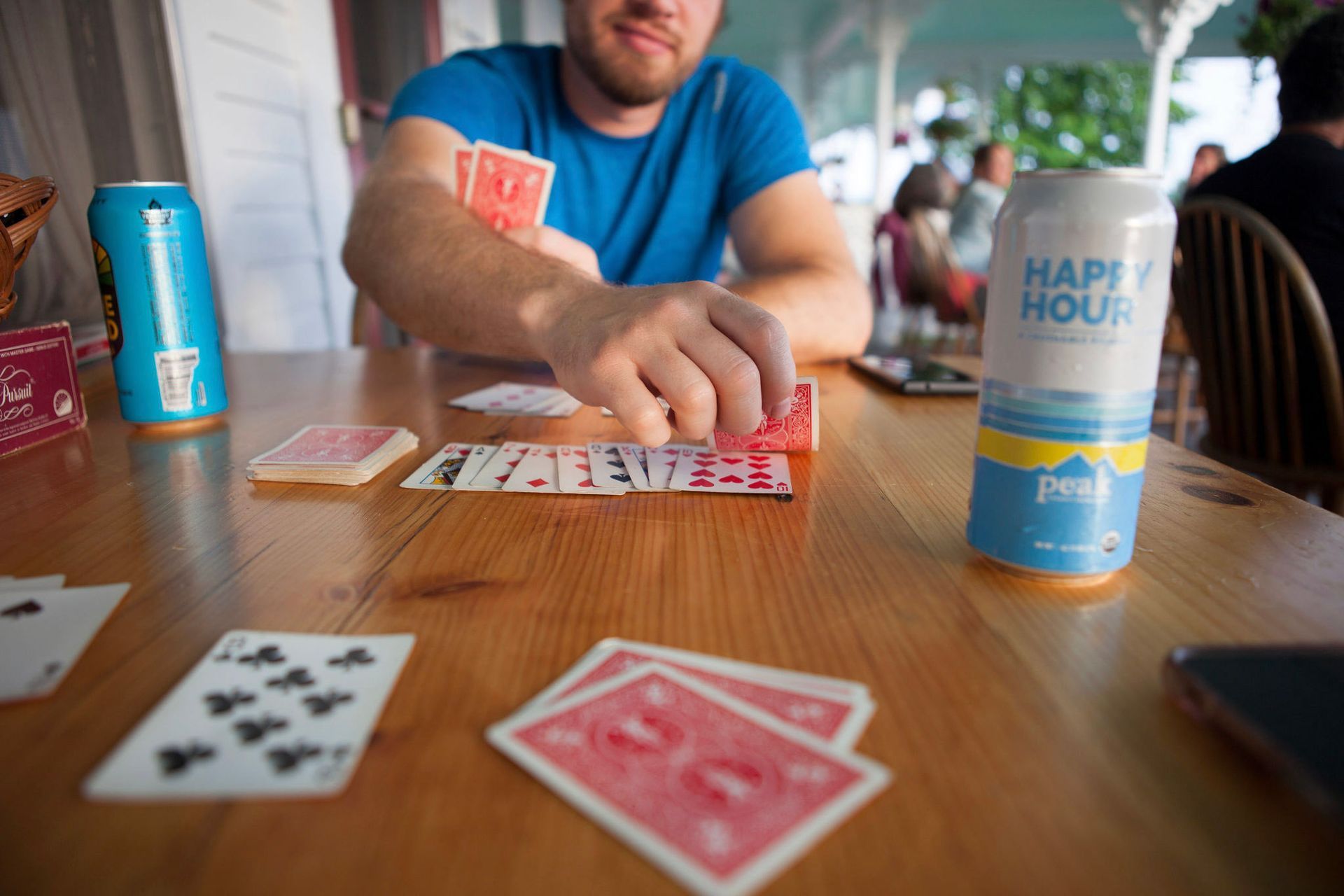 Man playing cards at a table with a can of 