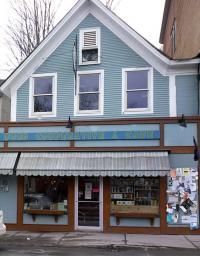 Blue storefront with awning, three windows on the second floor.