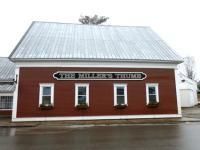 Red building with white trim and a metal roof. Sign reads