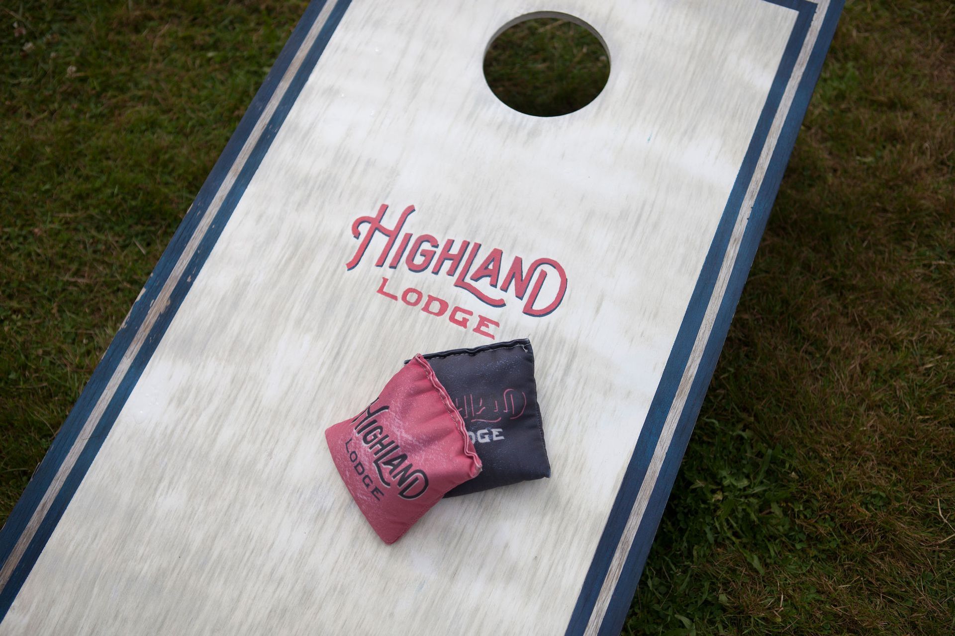 Cornhole board with two bean bags, grass, and 