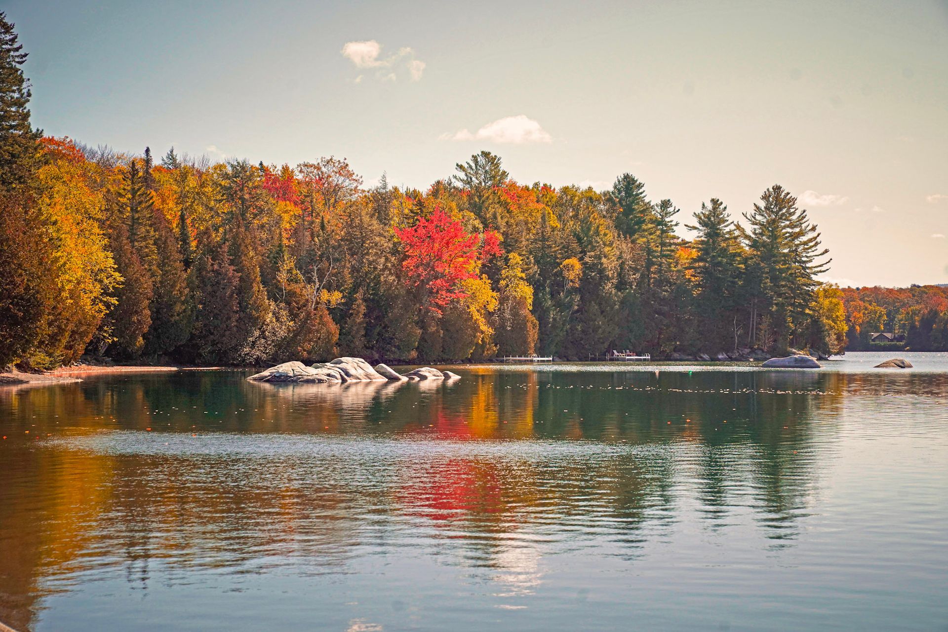 Autumn lake with colorful trees reflected in the water under a clear blue sky.