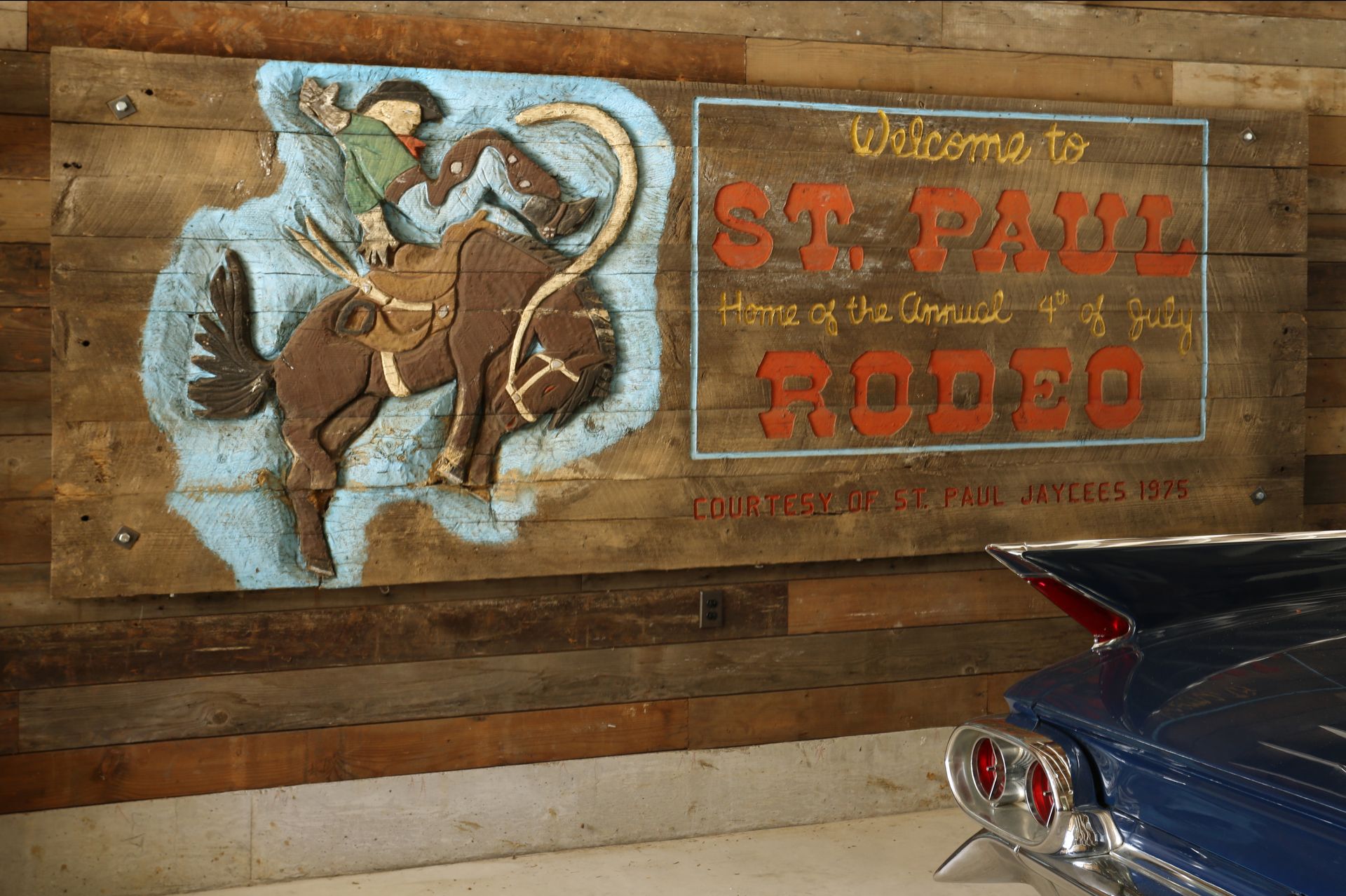 A large vintage St Paul Rodeo sign hangs prominently in the restored garage on salvaged paneling.