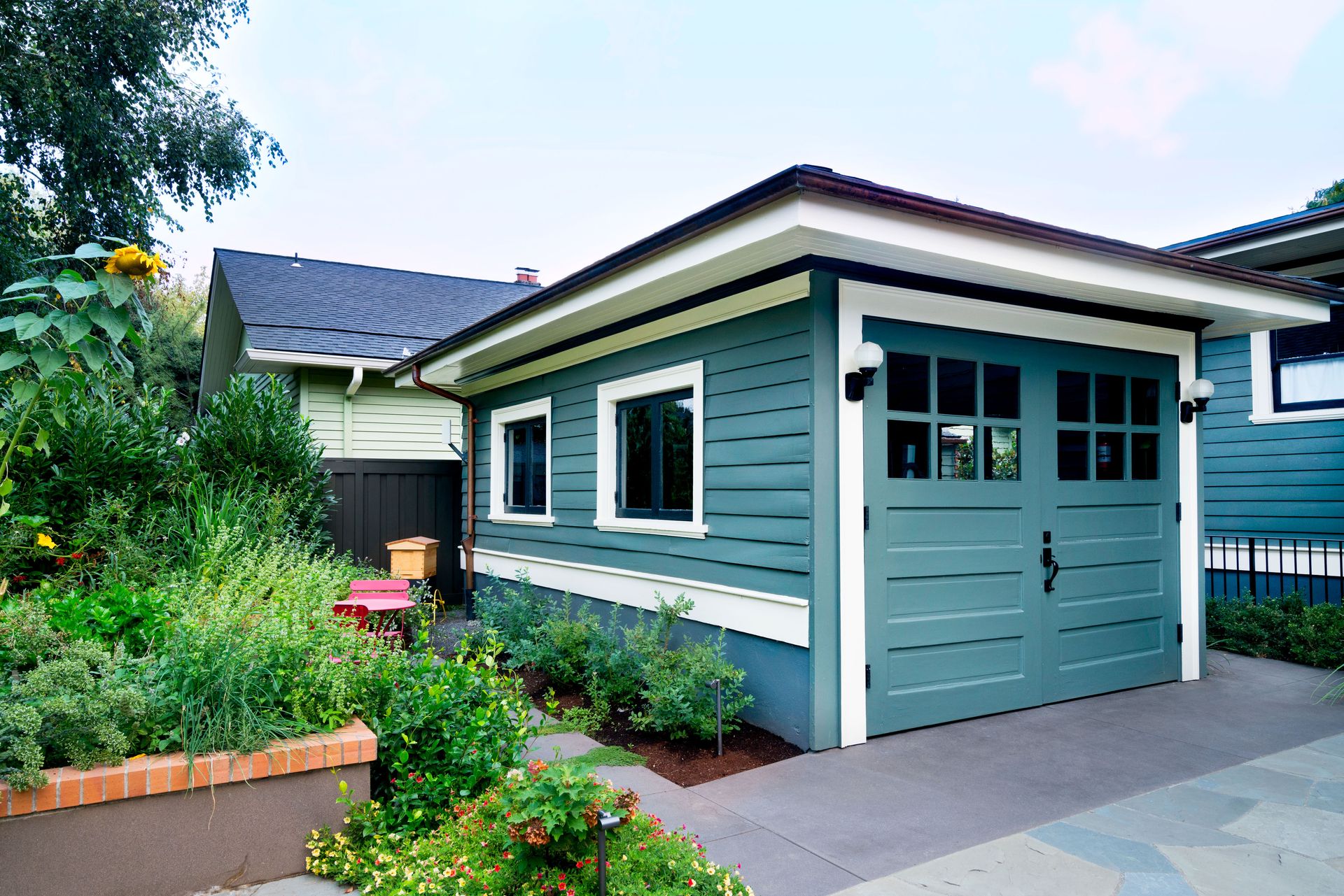 Refurbished garage painted in blue green with creamy white trim with new windows and a new pair of doors.