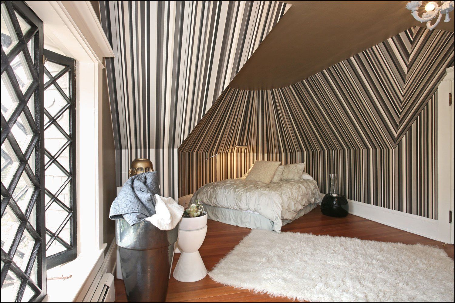 Playful black and white striped wallpaper emphasizes dramatic roof lines in the guest room.