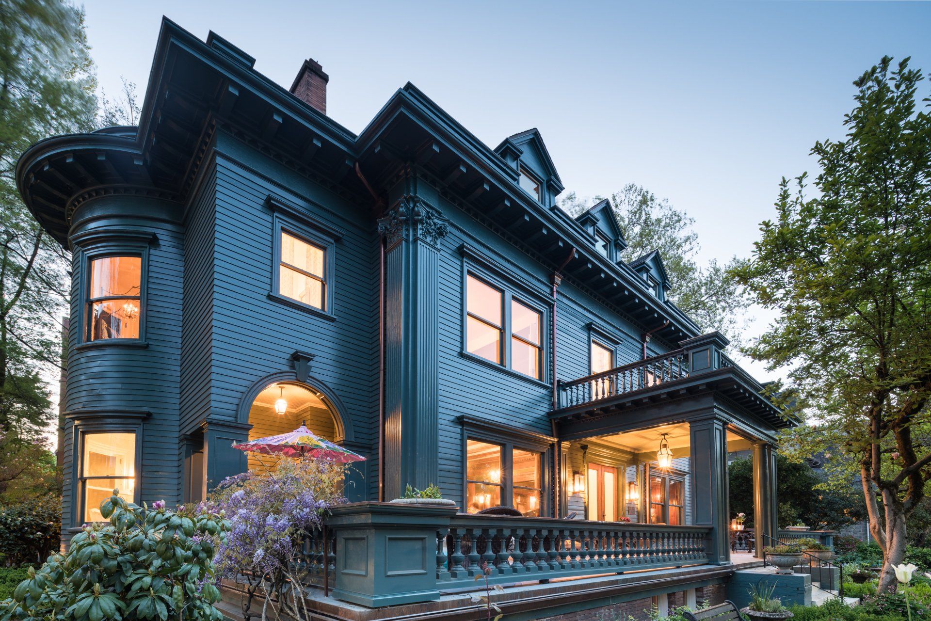 Large dark-teal Colonial mansion lit during twilight hours in the spring. 1904 Colonial Revival Mansion - Isam White House by Whidden & Lewis